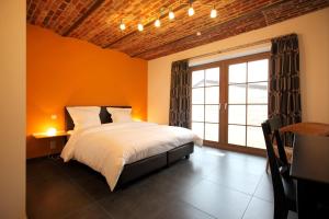 una camera da letto con pareti arancioni, un letto e una finestra di B&B Back2Front a Boezinge