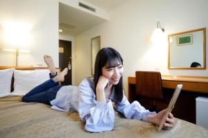 een vrouw op een bed met een laptop bij Kawasaki Central Hotel in Kawasaki