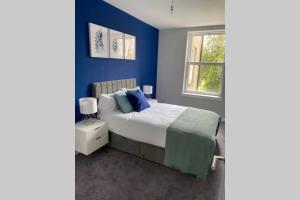 a blue bedroom with a bed and a window at Stunning 2 Bedroom River View Apartment in Perth