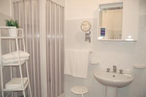 a white bathroom with a sink and a shower at Case Vacanze Farchikalà in Lampedusa