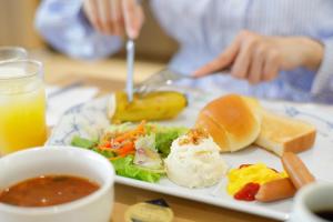 a plate of food with a salad and bread and orange juice at Kawasaki Central Hotel in Kawasaki