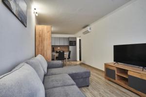 a living room with a couch and a flat screen tv at Cadet Apartments - hostAID in Siófok