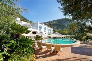 a pool with chairs and umbrellas in front of a building at Hotel Parco Smeraldo Terme in Ischia