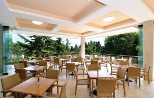 a restaurant with tables and chairs and a balcony at Kompas Hotel in Albena