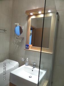 ein Badezimmer mit einem Waschbecken, einem Spiegel und einem WC in der Unterkunft Nia Családi Apartman in Bük