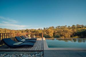 a deck with blue lounge chairs next to a pool at Monte Gois Country House e Spa in Curvatos