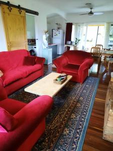 Sala de estar con sofás rojos y mesa de centro en Kyogle Comfy Homestay, en Kyogle