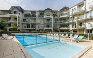 a swimming pool in front of a large apartment building at Vacancéole - Les Jardins de l'Amirauté in Les Sables-dʼOlonne