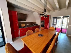 uma sala de jantar com uma mesa de madeira e armários vermelhos em Blomsteech em Holwerd