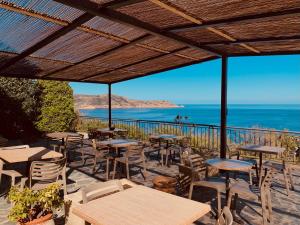 een patio met tafels en stoelen en uitzicht op de oceaan bij Il Tramonto in Calvi