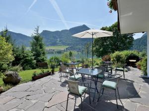 um pátio com uma mesa, cadeiras e um guarda-sol em Rosenhof am See em Thiersee