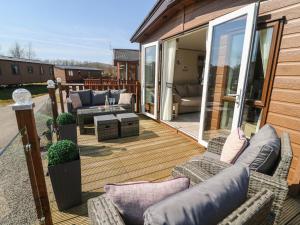 eine Terrasse mit Sofas und Stühlen auf einer Terrasse in der Unterkunft Lancaster Lodge in Carnforth