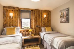 two beds in a room with wooden walls at Tipperary House Dublin in Dublin