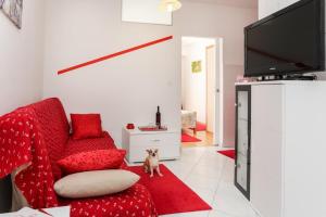 a living room with a red couch and a dog sitting on a red rug at Apartments Pojko in Dubrovnik