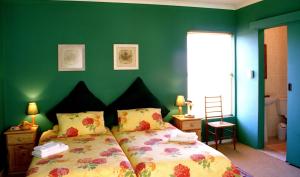 een slaapkamer met een bed met een groene muur bij Blue Mountain Guest House in Bloubergstrand