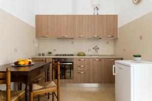 una cocina con armarios de madera y una mesa con un bol de fruta en Casa Vintage con terrazza by Wonderful Italy, en Ostuni