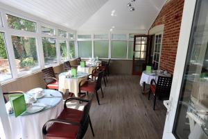 a dining room with tables and chairs and windows at Ormonde House Hotel in Lyndhurst