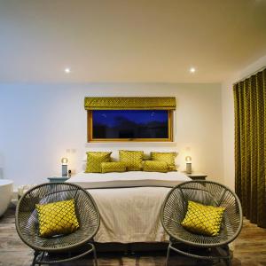 ein Schlafzimmer mit einem großen Bett und zwei Stühlen in der Unterkunft Ardtorna in Benderloch