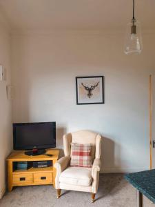 a living room with a chair and a television at Apartment D 4 Battery Terrace Oban in Oban