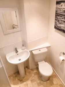 a white bathroom with a toilet and a sink at Apartment D 4 Battery Terrace Oban in Oban