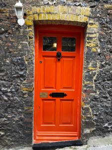 an orange door on a stone wall with a lamp at Old Barrel Store - Old Town. Parking & Garden in Margate