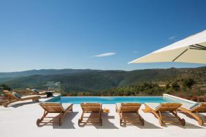 a group of chairs and an umbrella next to a swimming pool at Villa Selene in Rabac