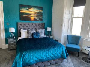 ein blaues Schlafzimmer mit einem Bett und einem blauen Stuhl in der Unterkunft Ashburn House in Fort William