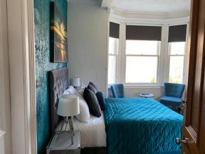 a bedroom with a blue bed and a window at Ashburn House in Fort William