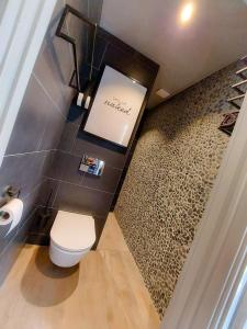a bathroom with a toilet and a tile wall at Snurk Texel in Den Burg
