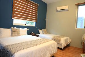 two beds in a room with blue walls and a window at 500Km Home in Hualien City