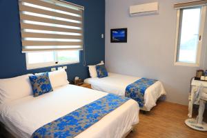 two beds in a room with blue walls and windows at 500Km Home in Hualien City