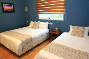 two beds in a room with blue walls and a window at 500Km Home in Hualien City