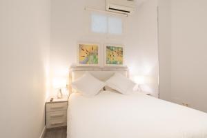 a white bedroom with a white bed and two lamps at Homemalaga Constitución in Málaga