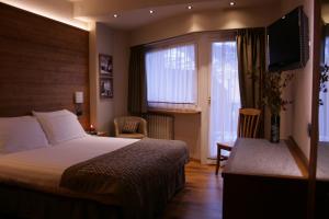 um quarto de hotel com uma cama e uma grande janela em Hotel Larice Bianco em Bormio