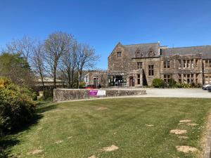 a large stone building with a grass field in front of it at 13 The Park in Kilkhampton