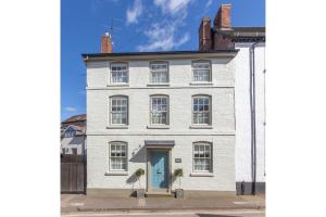 a white house with a blue door on a street at Turford House, Ludlow in Ludlow