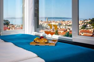 ein Bett mit einem Tablett mit Brot und einem Glas Wein in der Unterkunft Villa Venka in Rab