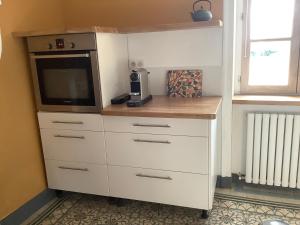 a white dresser with a microwave and a television at Pivoines in Saint-Julien
