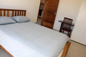 卢萨卡!! The ranch - Superb serviced apartment with garden的一间卧室，里面有一张床、一张桌子和一把椅子