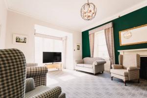 a living room with chairs and a tv and a fireplace at Wallace Apartment - A unique apartment in countryside park with WIFI and access to bar and pool in Perth