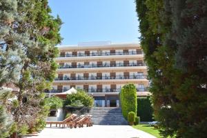ein großes Gebäude mit Bänken und Bäumen davor in der Unterkunft Merope Hotel in Karlovasi
