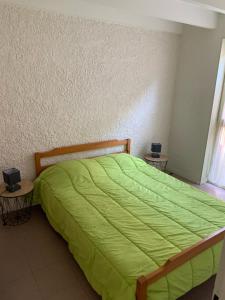 een slaapkamer met een groen bed en 2 tafels bij Camping Le Saillet in Lestelle-Bétharram