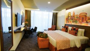 ナイロビにあるSarova Panafric Hotelのベッド、デスク、テレビが備わるホテルルームです。