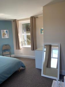 a bedroom with a bed and a mirror at Homewood Airbnb, Combe Martin, Devon - 300m to the Beach! in Combe Martin