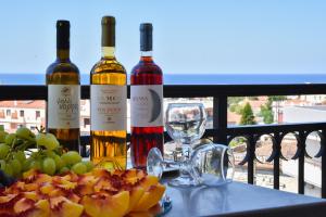 Drei Flaschen Wein stehen mit Weingläsern auf einem Tisch. in der Unterkunft Merope Hotel in Karlovasi