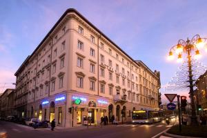 un gran edificio blanco en una calle de la ciudad por la noche en Victoria Hotel Letterario, en Trieste