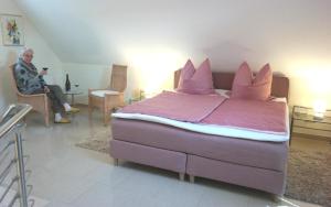 a man sitting in a room with a large bed at Modernes 5-Sterne-Ferienhaus im Maisonettenstil in DAMP in Damp