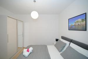 een witte slaapkamer met een bed met een roze knuffeldier erop bij Studio apartments Kalma in Dubrovnik
