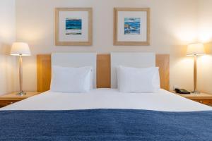 a bedroom with a large white bed with two lamps at Maritim Antonine Hotel & Spa in Mellieħa