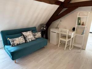 a living room with a blue couch and a desk at Les sureaux du cher in Noyers-sur-Cher